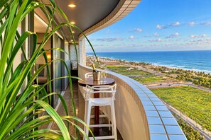 A balcony with a view of the ocean and a cityscape. - Cobertura vista mar com deck privativo (Fortaleza)