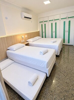 A hotel room with two beds, a wardrobe, an air conditioning unit, and a wall-mounted light fixture. - Cobertura vista mar com deck privativo (Fortaleza)