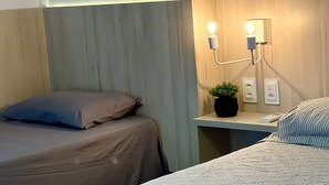 A hotel room with two beds, a nightstand with a lamp, and a wall-mounted light fixture. - Cobertura vista mar com deck privativo (Fortaleza)