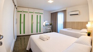 Ein Hotelzimmer mit zwei Betten, einem Schreibtisch und einem Kleiderschrank.