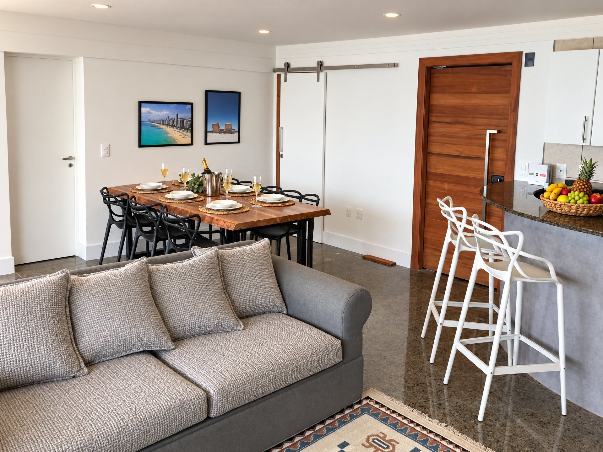 A modern living space with a dining area, a sofa, a kitchen bar, and a sliding door.