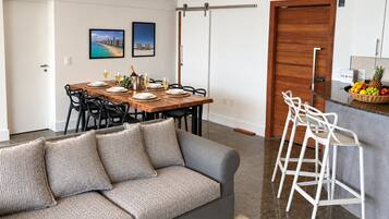 A modern living space with a dining area, a sofa, a kitchen bar, and a sliding door.