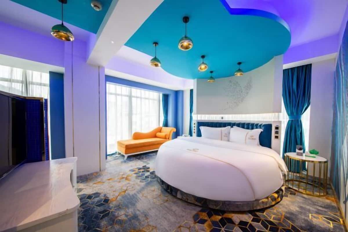 A modern hotel room with a large bed, a sofa, and a small table.