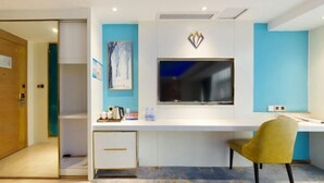 A modern hotel room with a white desk, a flat-screen TV, a small cabinet, and a yellow chair. - the Diamond Hotel (Yanting)