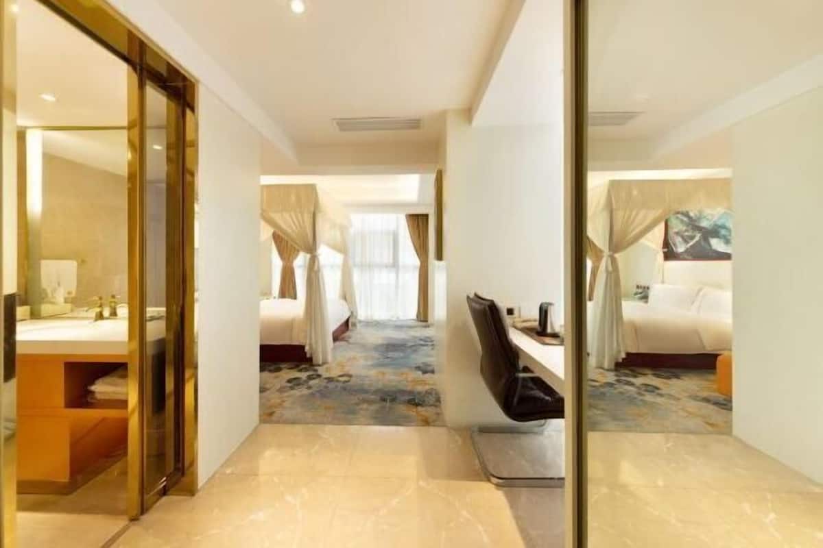 A hotel room with a large bed, a desk, and a bathroom with a mirror and sink.