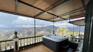 Un balcon avec un jacuzzi, une vue sur les montagnes et un sol carrelé.