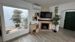 Un salon doté d’une cheminée, d’un téléviseur fixé au mur et d’une grande fenêtre donnant sur un jardin.