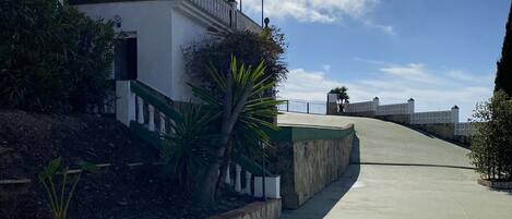 A building with a white facade, a balcony with white balustrades, and a stone retaining wall.