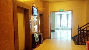A hotel lobby with a marble wall, a reception desk, a television, and a staircase. - Zhongjing Hotel (Fangchenggang)