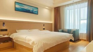 A hotel room with a large bed, a bedside table, a chair, and a window with curtains. - Zhongjing Hotel (Fangchenggang)