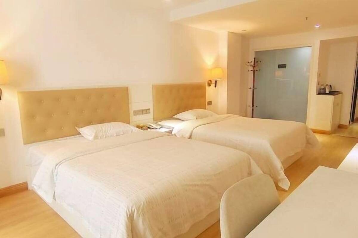 Een hotelkamer met twee bedden, een bureau en een deur naar de badkamer.