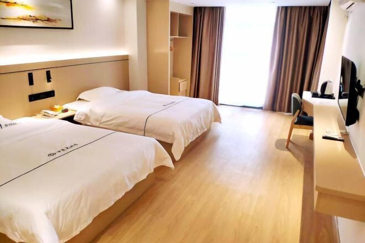 Een hotelkamer met twee bedden, een bureau, een stoel en een kledingkast.