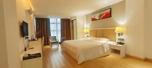 Ein Hotelzimmer mit einem Bett, Nachttischen, einem Fernseher, einem Sessel und einem Bild an der Wand.