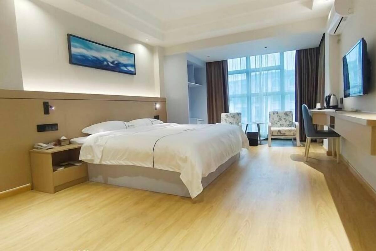 Een moderne hotelkamer met een groot bed, een bureau, een stoel en een televisie.
