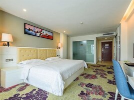 Una habitación de hotel con cama, mesitas de noche, un escritorio y una silla.