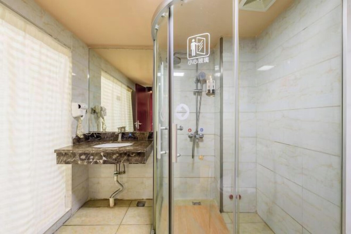 Een moderne badkamer met een douchecabine van glas, een marmeren wastafel en een spiegel.