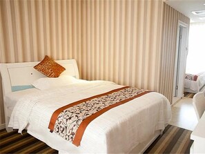 Ein Hotelzimmer mit einem Bett, einem Kissen, einem gestreiften Vorhang und einer Tür.