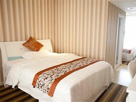 Una habitación de hotel con cama, almohada, cortina a rayas y una puerta.