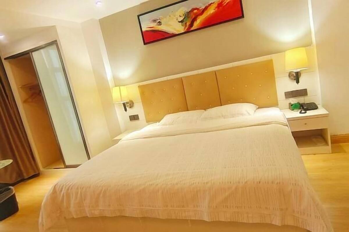 Een hotelkamer met een groot bed, nachtkastjes, een lamp en een schilderij aan de muur.