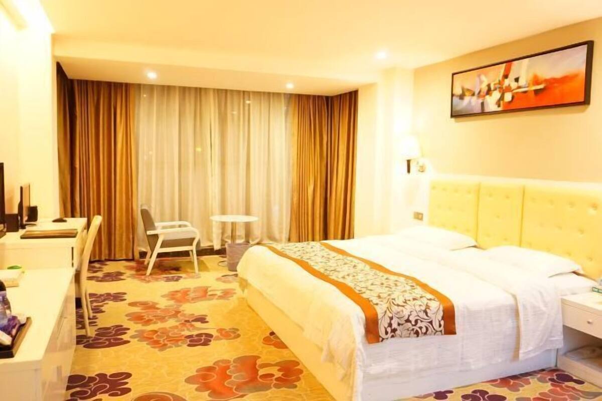 Een hotelkamer met een bed, bureau, stoel en gordijnen.