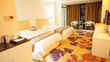 A hotel room with two beds, a desk, a chair, and a small table.