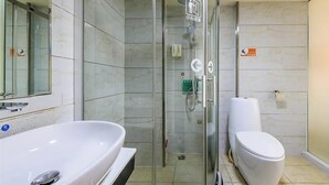 Une salle de bain moderne avec une douche à parois de verre, un lavabo blanc et des toilettes.