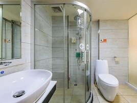 Un baño moderno con ducha acristalada, lavamanos blanco y un inodoro.