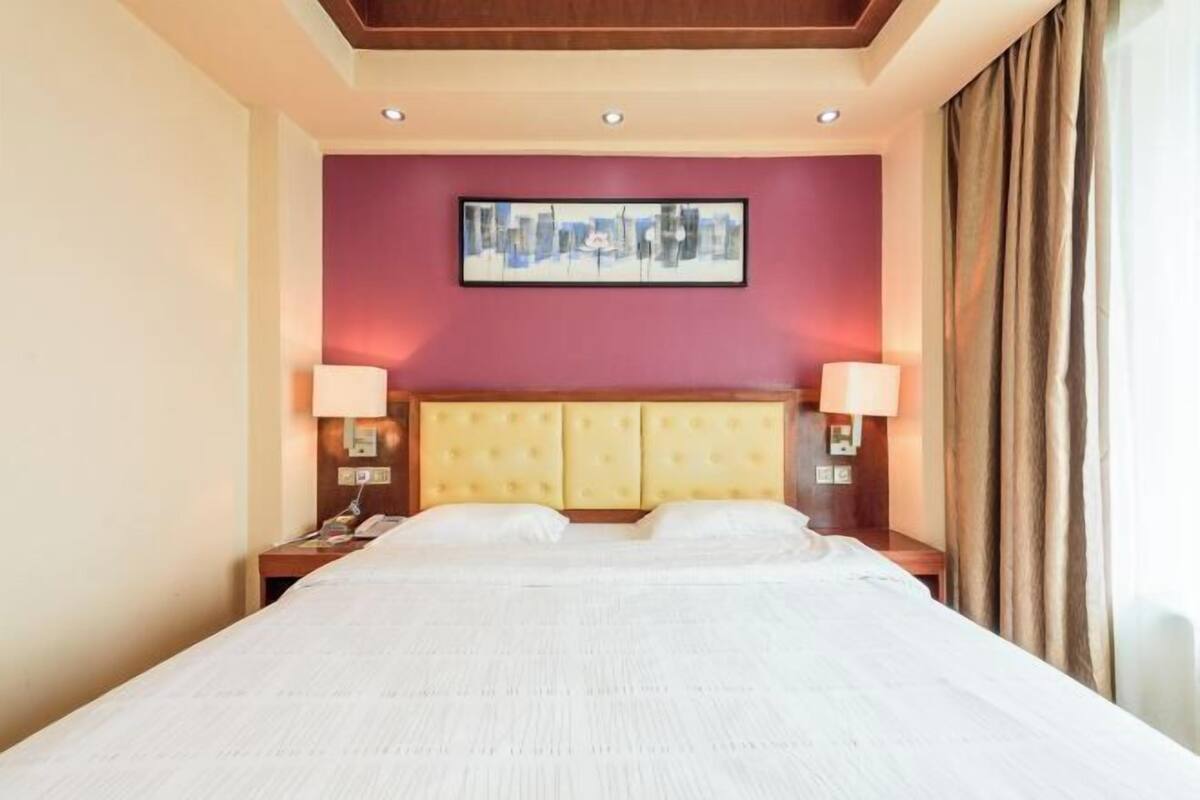Een hotelkamer met een groot bed, twee nachtkastjes, een hoofdbord en een lijst met kunst aan de muur.