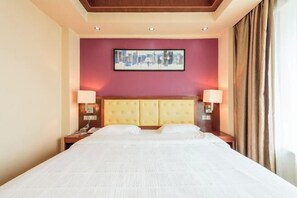 Une chambre d’hôtel avec un grand lit, deux tables de chevet, une tête de lit et une œuvre d’art encadrée au mur.