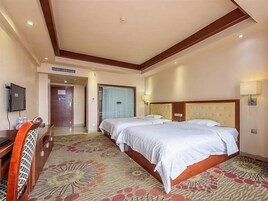 Una habitación de hotel con una cama grande, un escritorio, un televisor y una puerta que da a otra habitación.