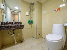 Un baño con inodoro, lavamanos, espejo, ducha y un cepillo verde de limpieza.