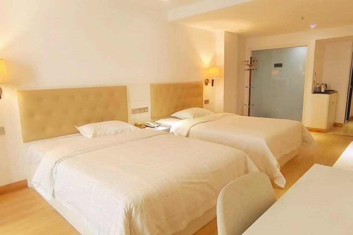 Een hotelkamer met twee bedden, een bureau en een deur naar de badkamer.
