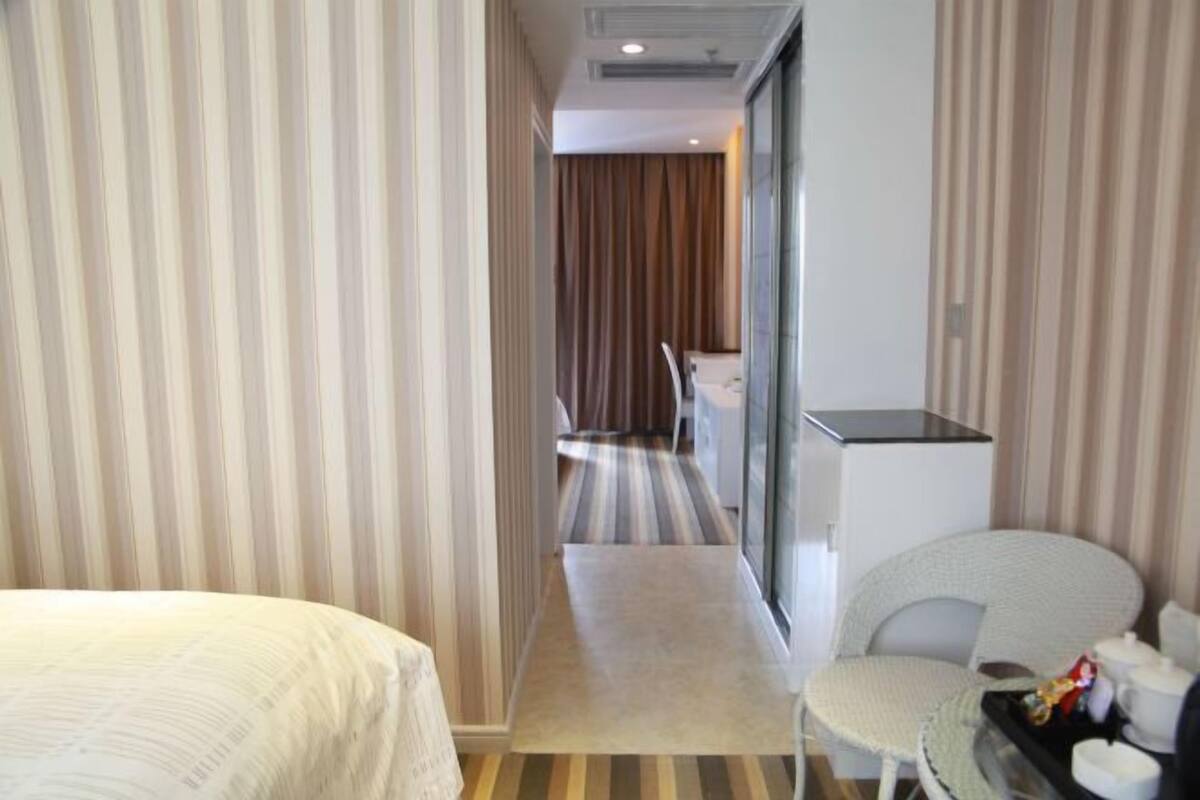 Een hotelkamer met een bed, een kleine tafel met stoel, een kitchenette en uitzicht op de gang.