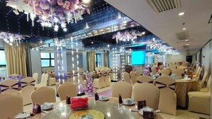 A spacious banquet hall with round tables, beige chairs, and a large screen. - Zhongjing Hotel (Fangchenggang)