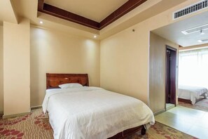 Une chambre d’hôtel avec un lit simple, une tête de lit en bois, une moquette à motifs et une porte donnant sur une autre pièce.