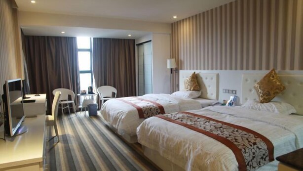 Une chambre d’hôtel avec deux lits, un bureau, une chaise et un téléviseur.