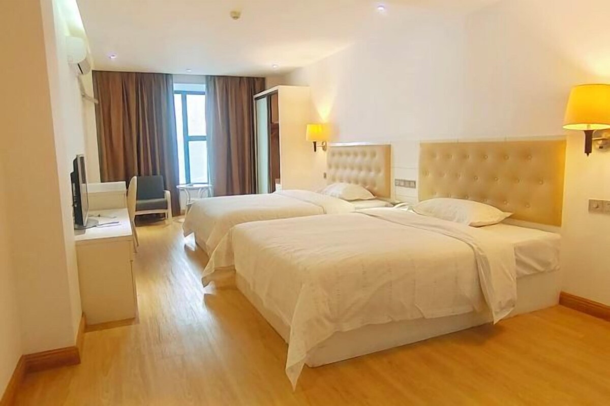 Une chambre d’hôtel avec deux lits, un bureau, une chaise et un téléviseur.