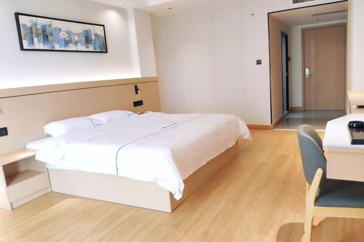 A modern hotel room with a large bed, a desk, and a chair.