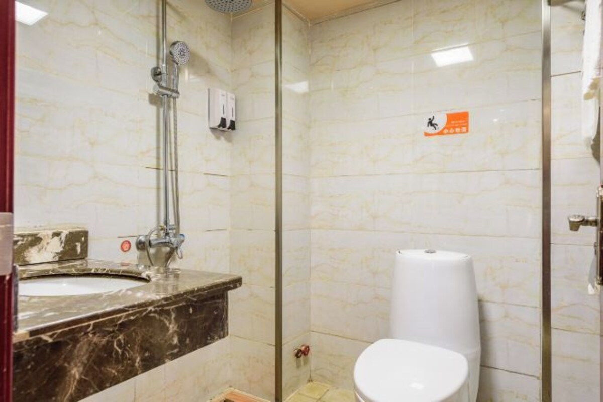 A bathroom with a marble sink, a toilet, and a glass-enclosed shower area.