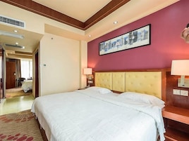 Habitación de hotel con una cama grande, cabecera, lámparas de noche y un cuadro en la pared.