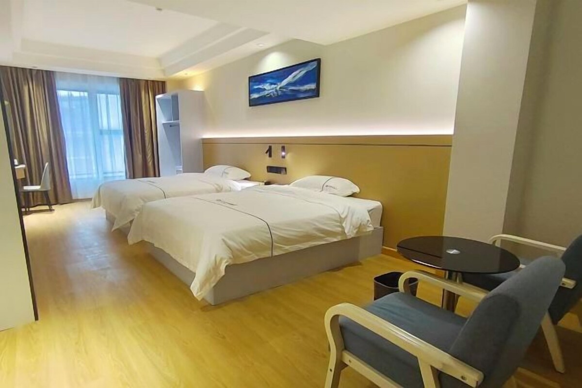 A hotel room with two beds, a small table, and a chair.