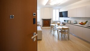 A modern kitchen with white cabinets, a dining area with a table and chairs, and a wooden floor. - Desenzanoloft Apa Dom  (Desenzano del Garda)