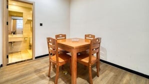 A room with a wooden dining table and four chairs, a wooden floor, and a white wall.