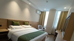 A hotel room with a large bed, a bedside table, a chair, a small table, and a TV mounted on the wall.