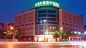A modern hotel with a prominent curved glass facade and illuminated signage.