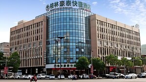 A modern hotel with a curved glass facade, multiple floors, and a prominent signage at the top. - Greentree Inn Huzhou Anji Yingbin Avenue Express Hotel (Huzhou)