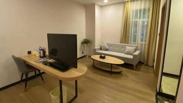 A modern living room with a wooden desk, a flat-screen TV, a sofa, and a coffee table.
