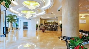 Un hall d’hôtel avec un sol en marbre, un comptoir d’accueil et une grande colonne.