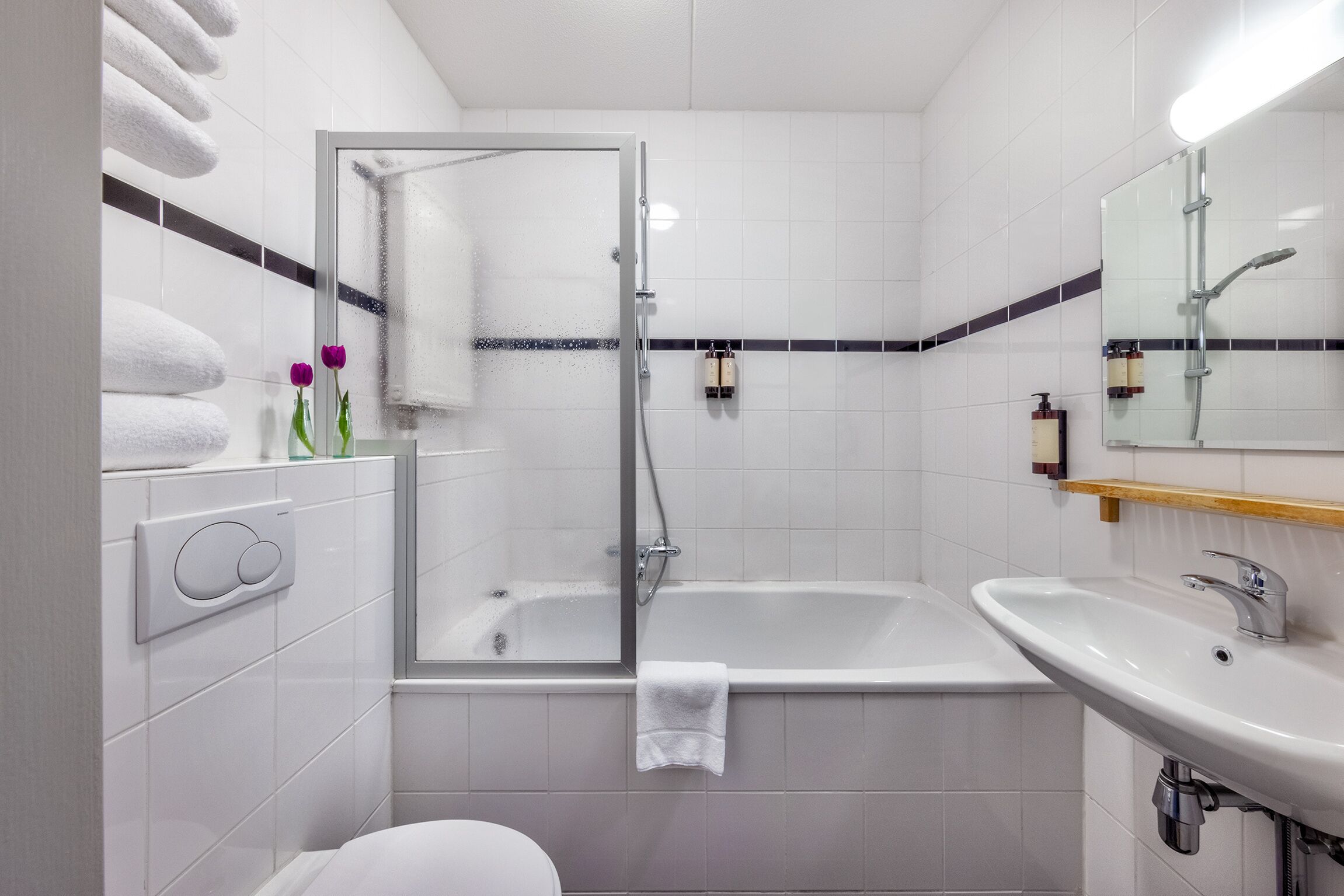 A modern bathroom with a glass-enclosed shower, a bathtub, and a sink.