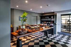 A buffet setup with a variety of dishes, a checkered floor, and a bookshelf with books and decorative items.